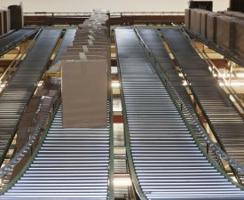 Cardboard boxes on conveyor belt in factory or warehouse.